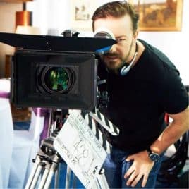 Ricky Gervais staring down the eyepiece of a camera.