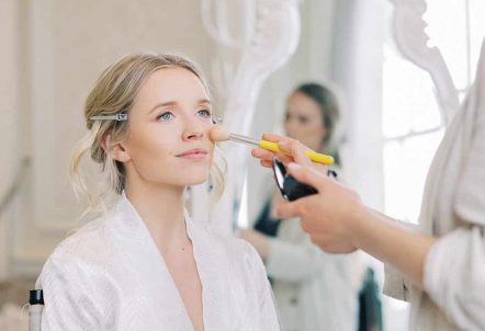 A bride on her wedding day getting her makeup done in the Alexander suite
